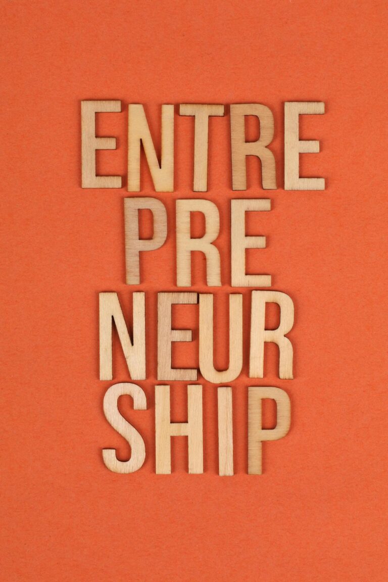 Wooden letters on orange background spelling 'ENTREPRENEURSHIP', symbolizing business aspirations.